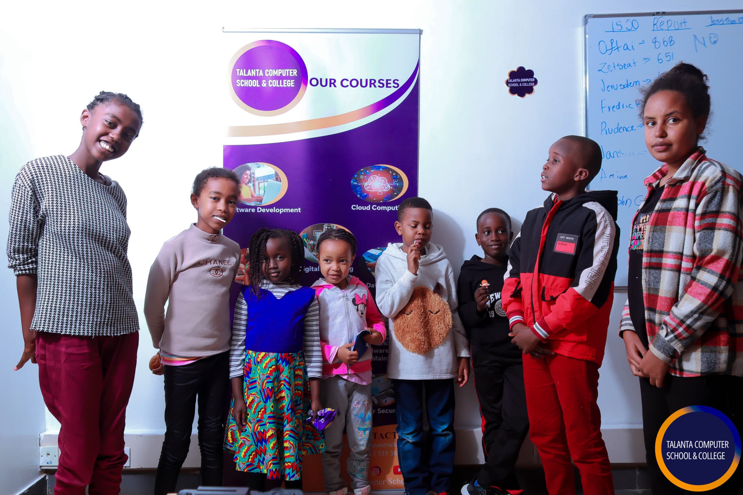 Children at a Talanta Tech Kids session in front of a Talanta banner