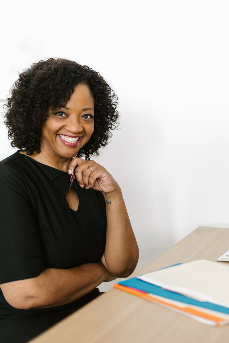 Happy woman sitting at a desk in a bright modern office, smiling confidently.