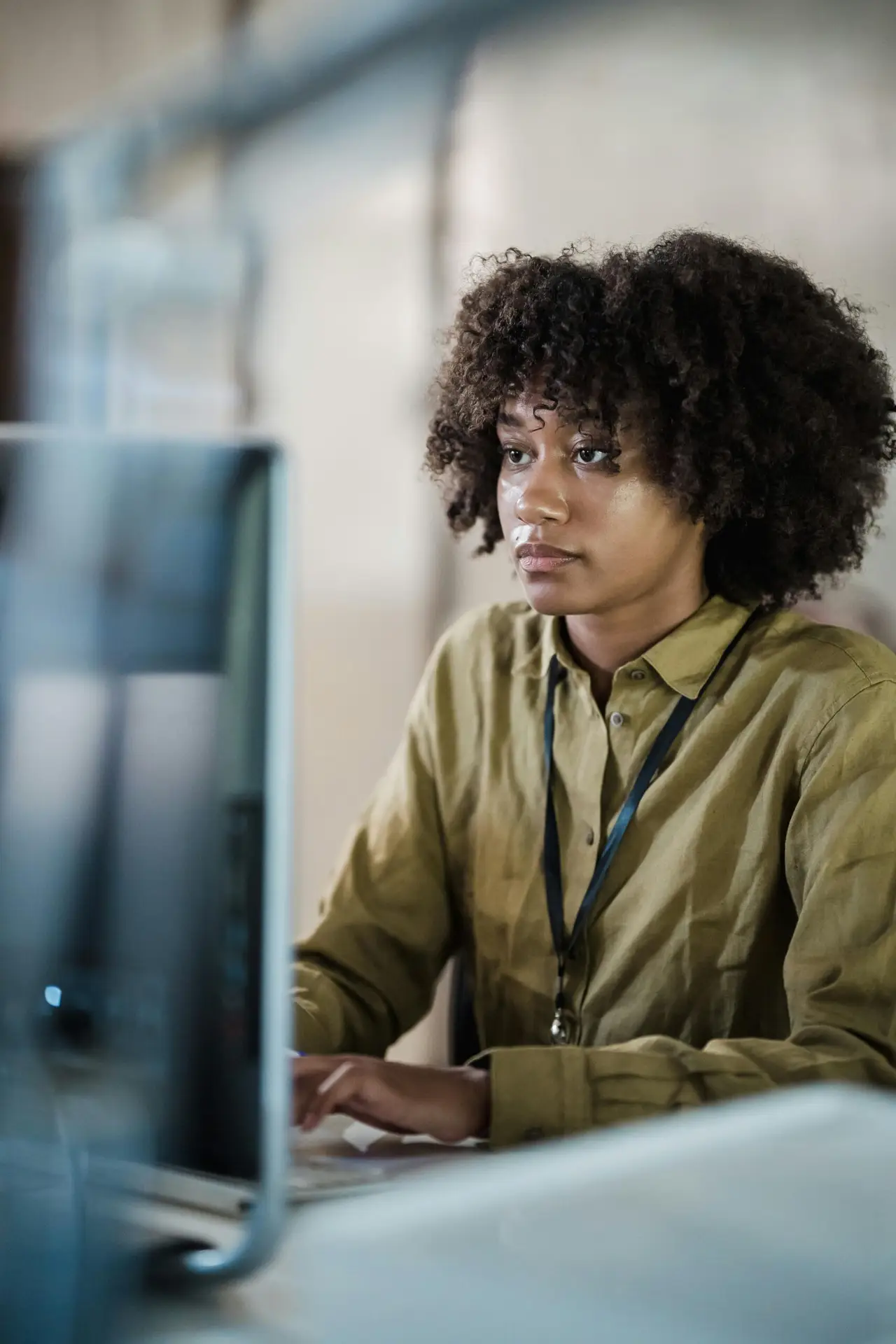 Focused young woman working at a computer in an office setting. Ideal for business and technology themes.